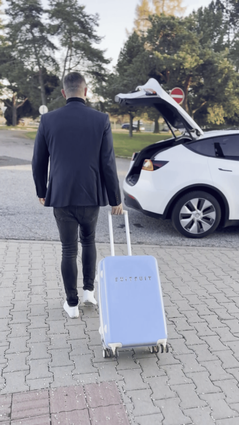 Cestujúci s kufrom nastupujúci do Tesly model Y